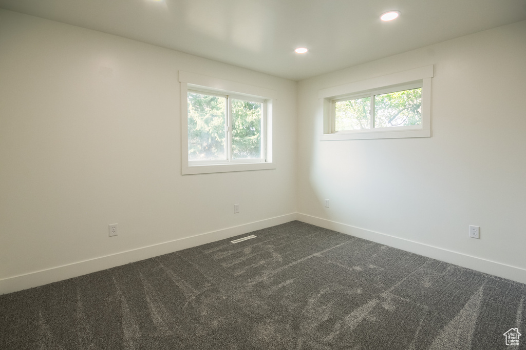 Empty room featuring dark carpet and recessed lighting
