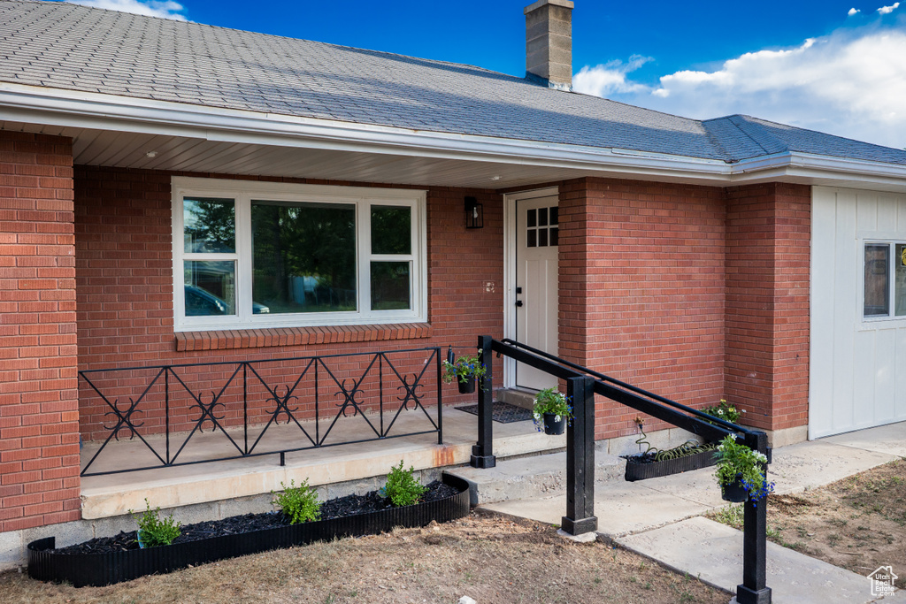 Entrance to property with brick siding and roof with shingles