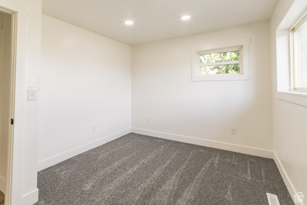 Empty room featuring dark carpet and recessed lighting