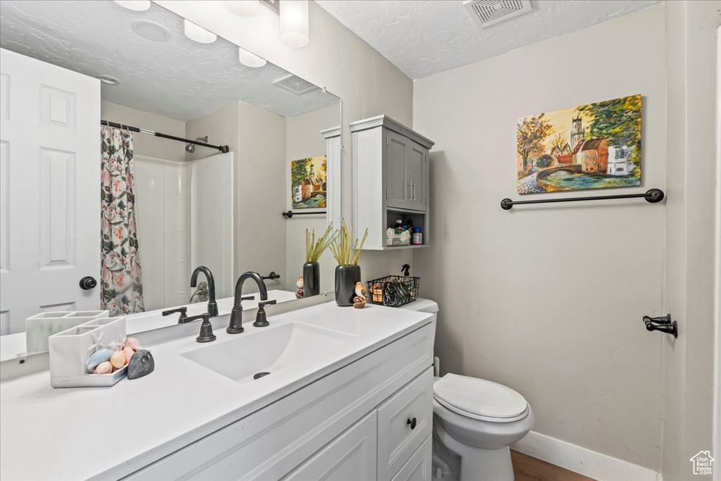 Full bath with vanity, a textured ceiling, a shower with shower curtain, and wood finished floors