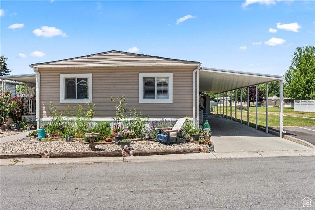 Manufactured / mobile home with a carport, concrete driveway, and a front lawn