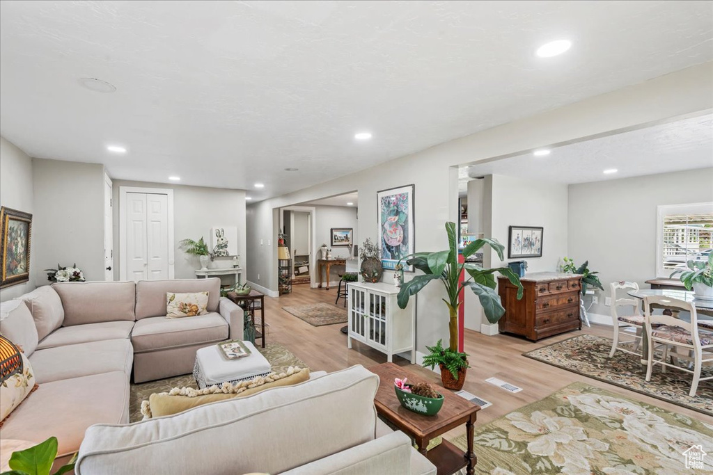 Living area with light wood-type flooring and recessed lighting