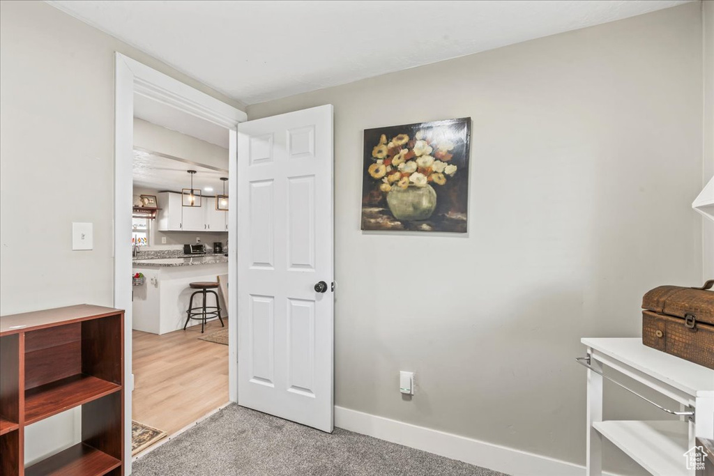 Hallway with baseboards and light colored carpet