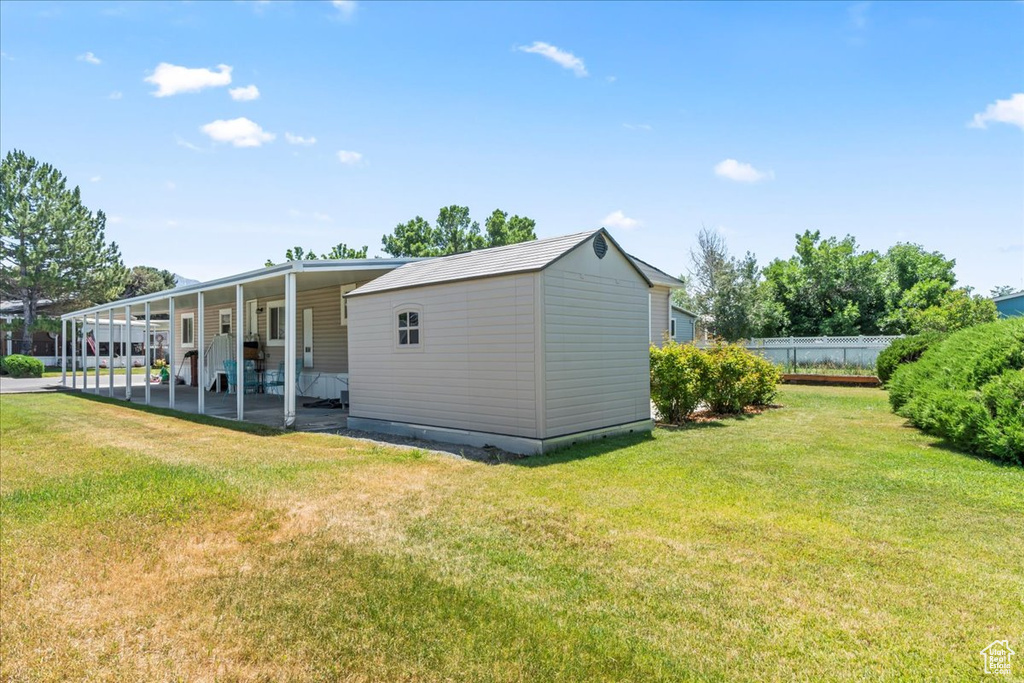View of side of property featuring an attached carport, an outbuilding, and a patio area