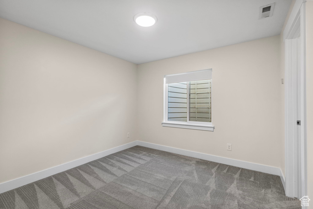 Carpeted spare room featuring baseboards