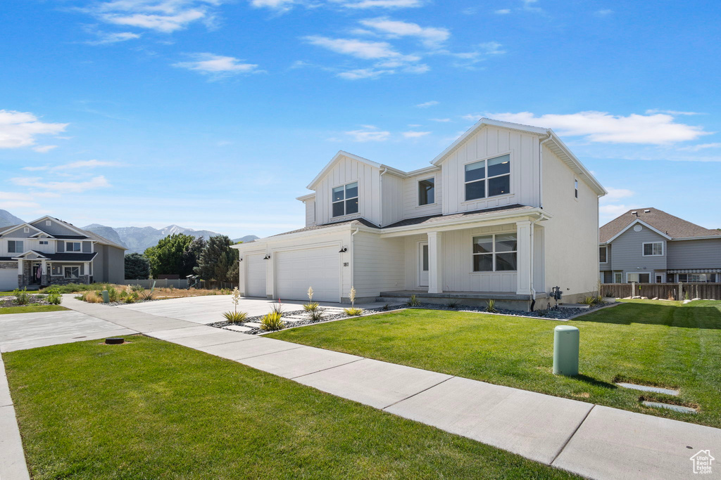 Modern farmhouse with board and batten siding, a garage, concrete driveway, and a mountain view