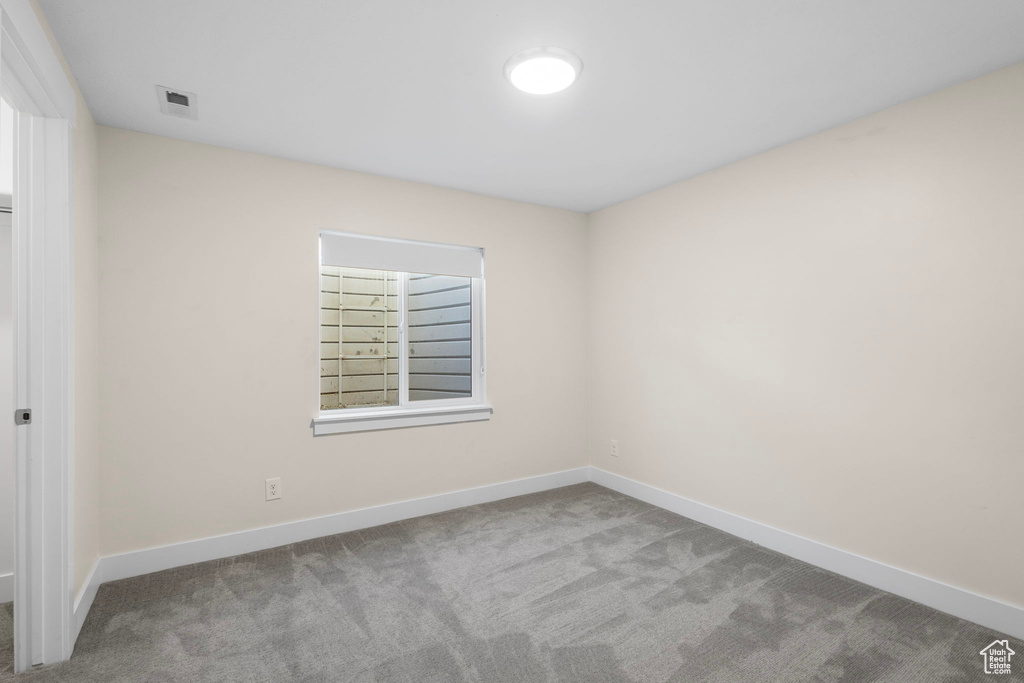 Carpeted spare room featuring baseboards