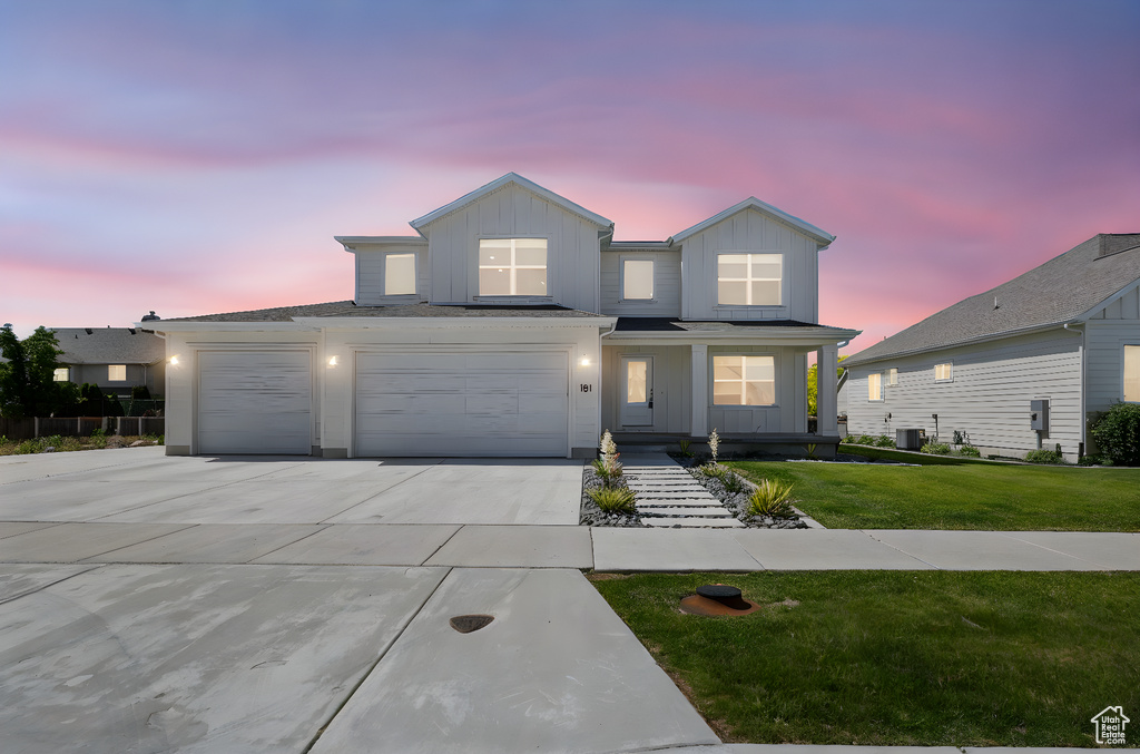 Traditional-style house featuring board and batten siding, concrete driveway, and a lawn