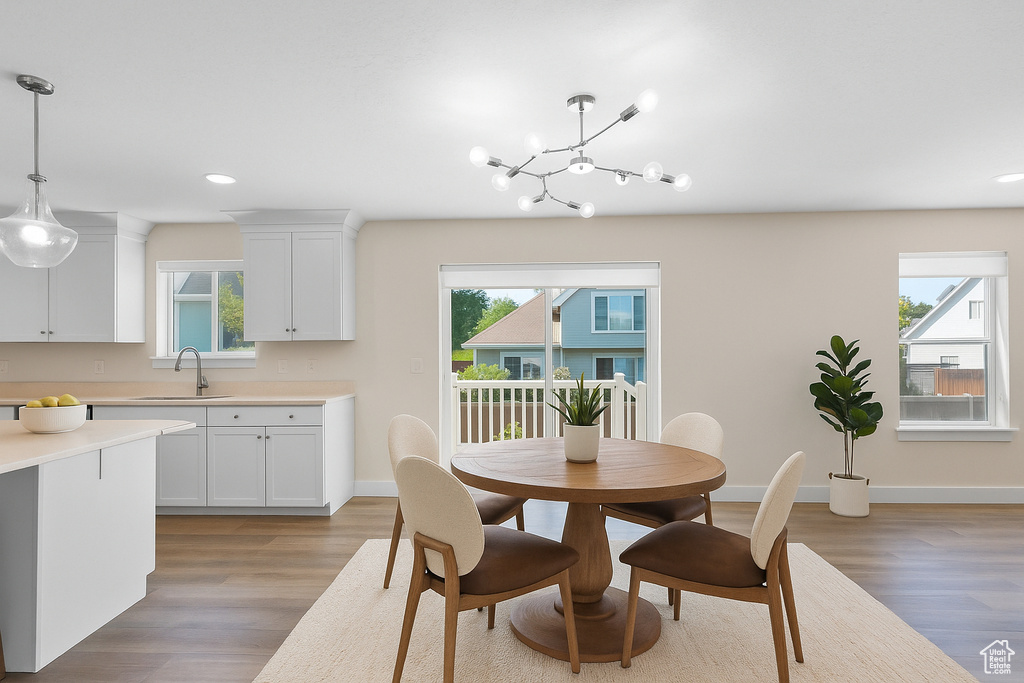 Dining room with healthy amount of natural light, light wood finished floors, recessed lighting, and a chandelier