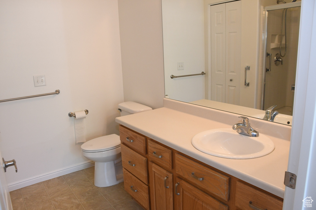 Bathroom with vanity, toilet, a shower with door, baseboards, and a closet