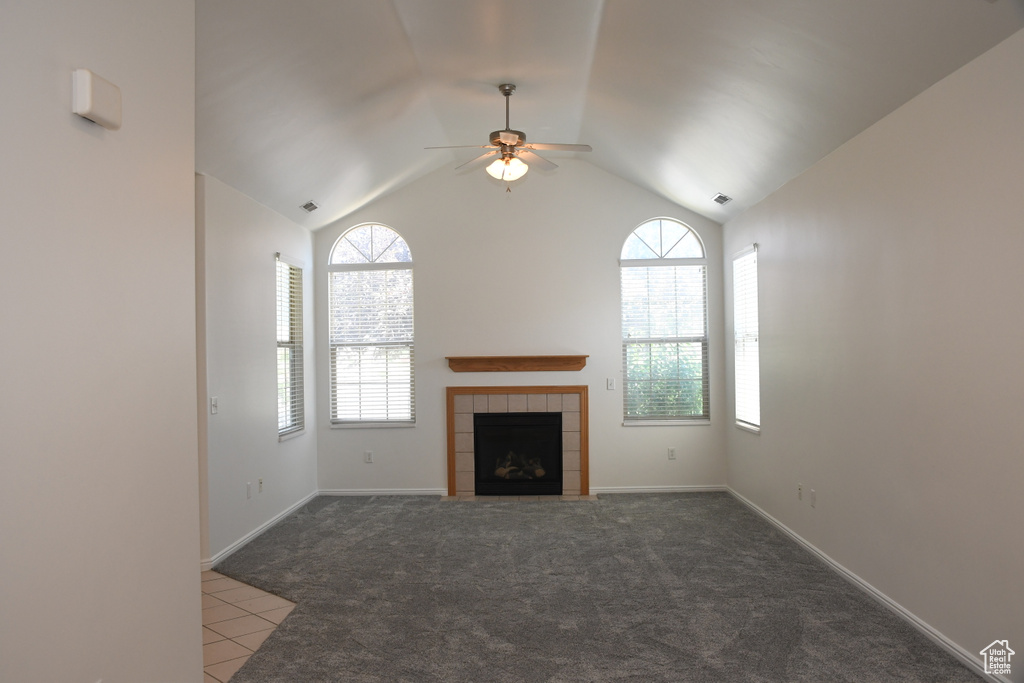 Unfurnished living room with a ceiling fan, a fireplace, carpet flooring, tile patterned flooring, and lofted ceiling