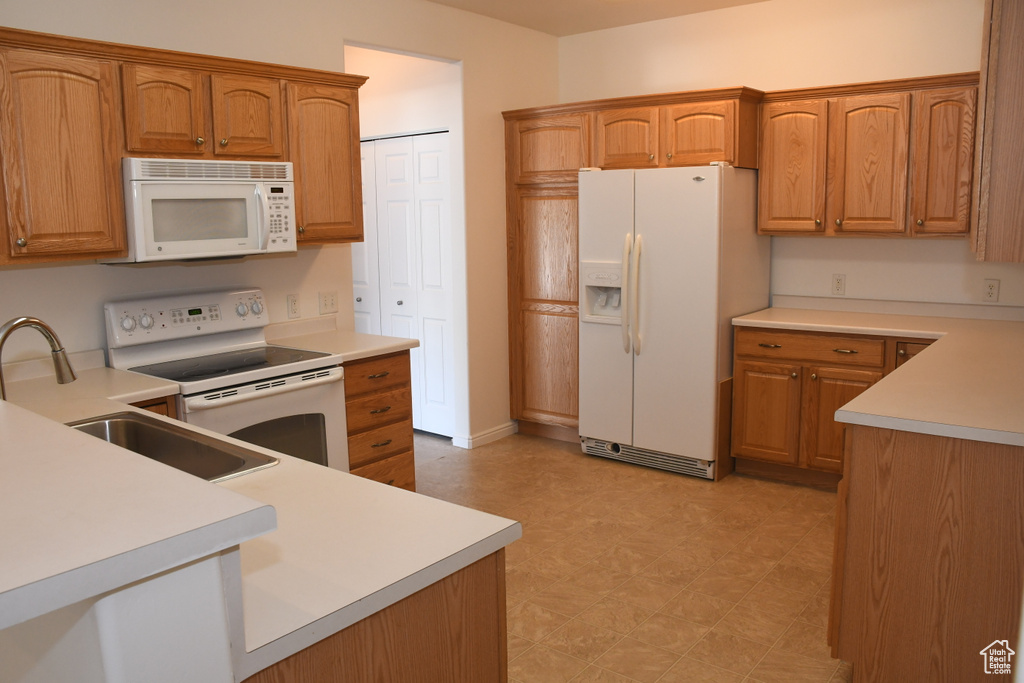 Kitchen featuring white appliances, light flooring, and brown cabinetry