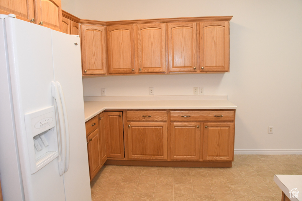 Kitchen with white refrigerator with ice dispenser and light countertops