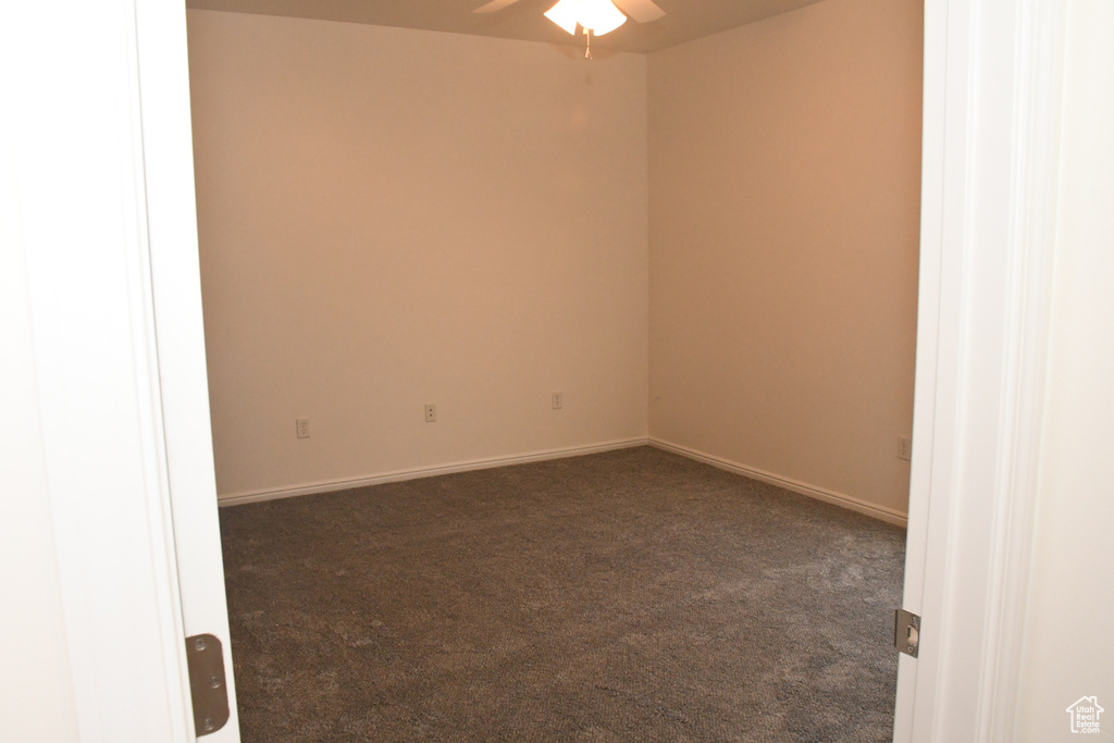 Unfurnished room with dark carpet, a ceiling fan, and baseboards