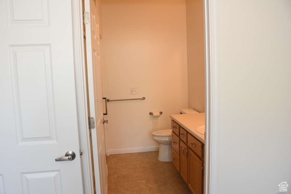 Bathroom featuring vanity, toilet, and baseboards
