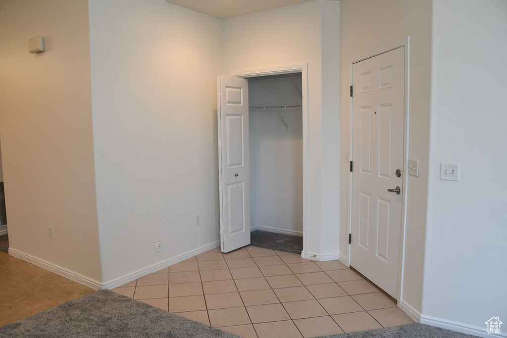Unfurnished bedroom with light tile patterned flooring, baseboards, and a closet