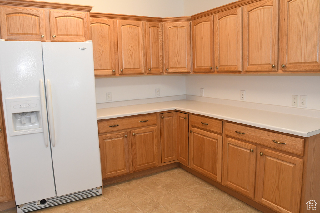 Kitchen featuring white refrigerator with ice dispenser, light countertops, and light flooring