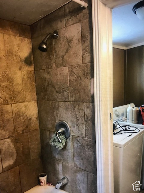 Bathroom view of washer / clothes dryer and shower / bathtub combination