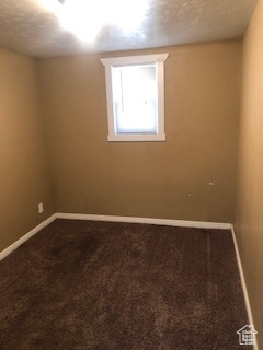 Unfurnished room featuring dark colored carpet