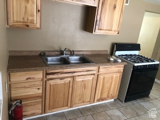 Kitchen featuring range with gas cooktop, dark countertops, and light brown cabinets