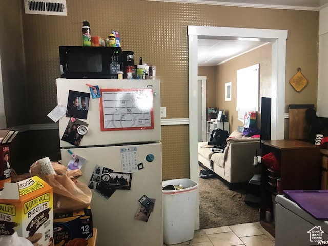 Interior space with ornamental molding, black microwave, and freestanding refrigerator
