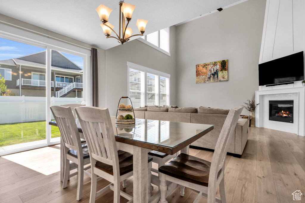 Dining area with light wood-type flooring, a chandelier, and a glass covered fireplace