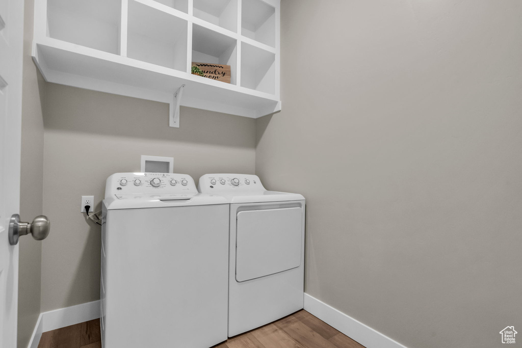 Washroom with washer and dryer and wood finished floors