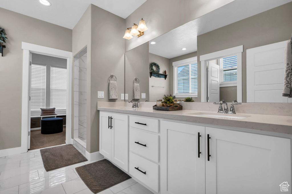 Bathroom featuring double vanity, tiled shower, recessed lighting, and marble finish flooring