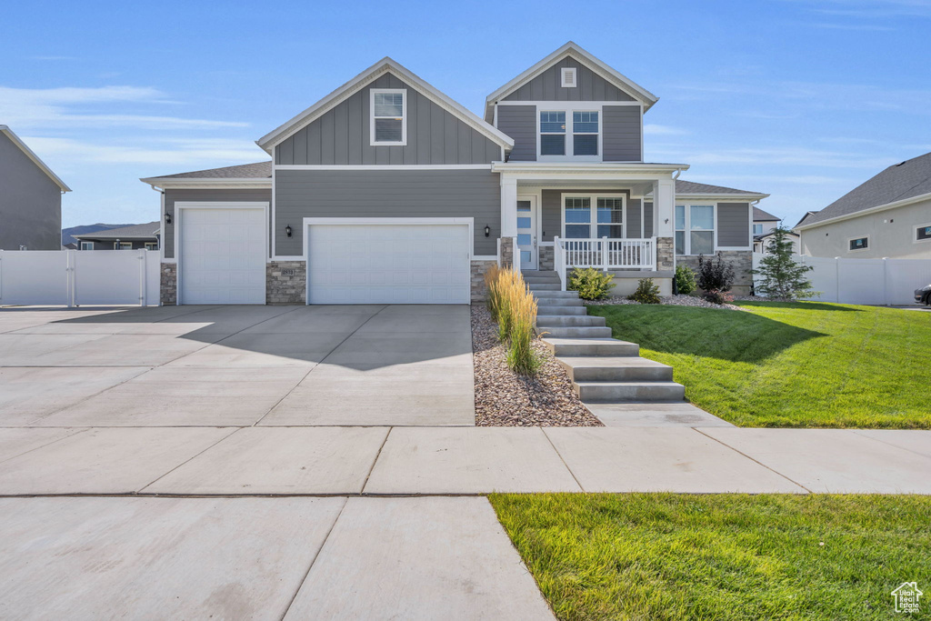 Craftsman-style house with stone siding, board and batten siding, and driveway