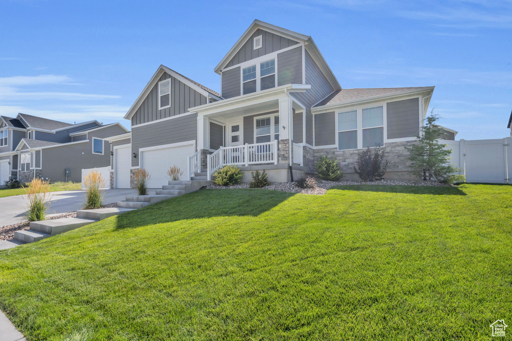 View of front of property with board and batten siding, concrete driveway, a porch, and stone siding