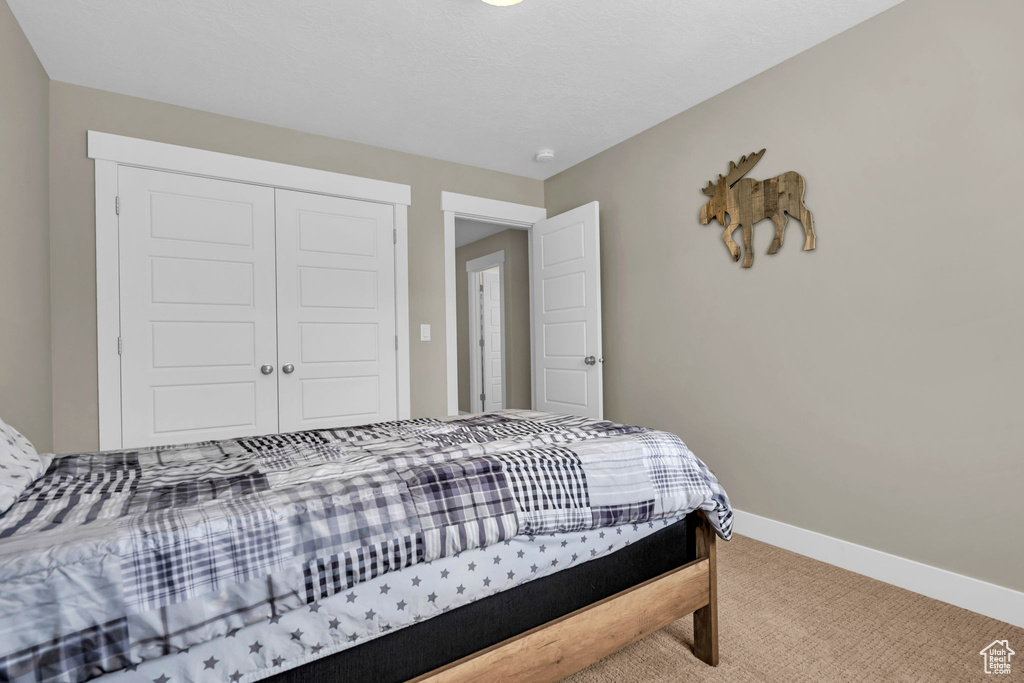 Carpeted bedroom featuring a closet and baseboards
