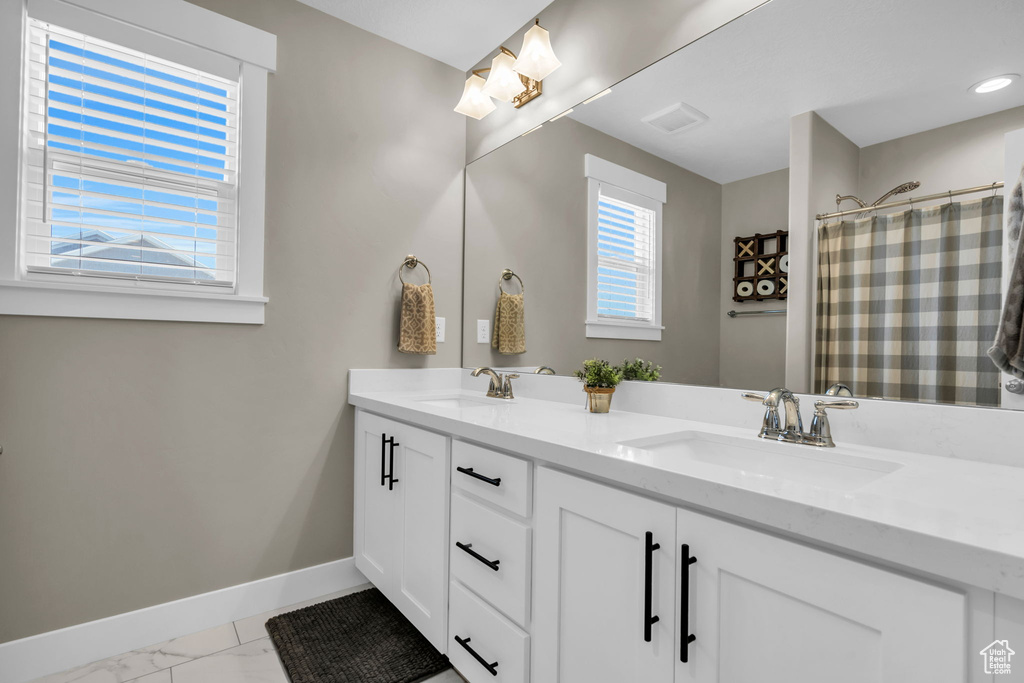 Bathroom featuring double vanity, marble finish floors, and curtained shower