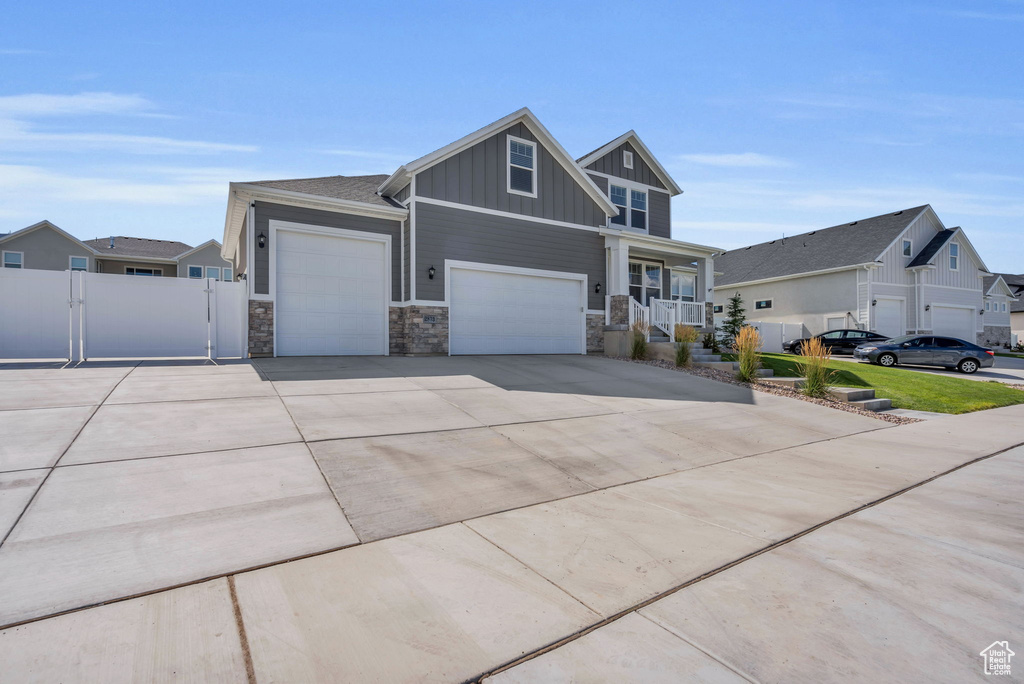 Craftsman inspired home featuring board and batten siding, stone siding, concrete driveway, and covered porch