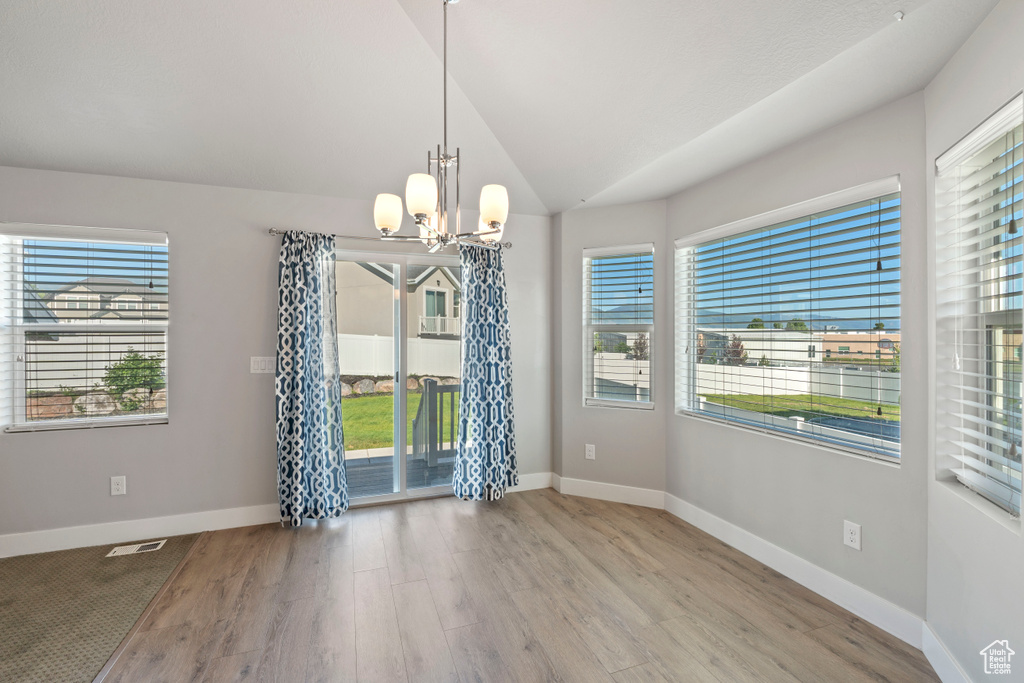 Empty room featuring a chandelier, wood finished floors, and lofted ceiling