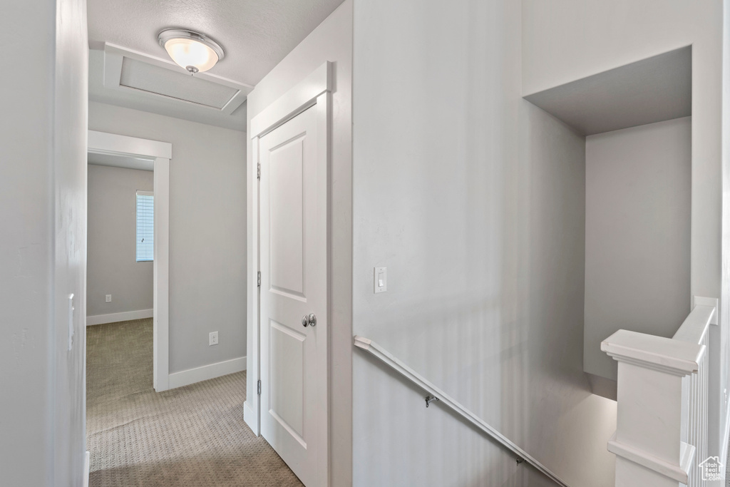 Hallway featuring an upstairs landing, attic access, and carpet