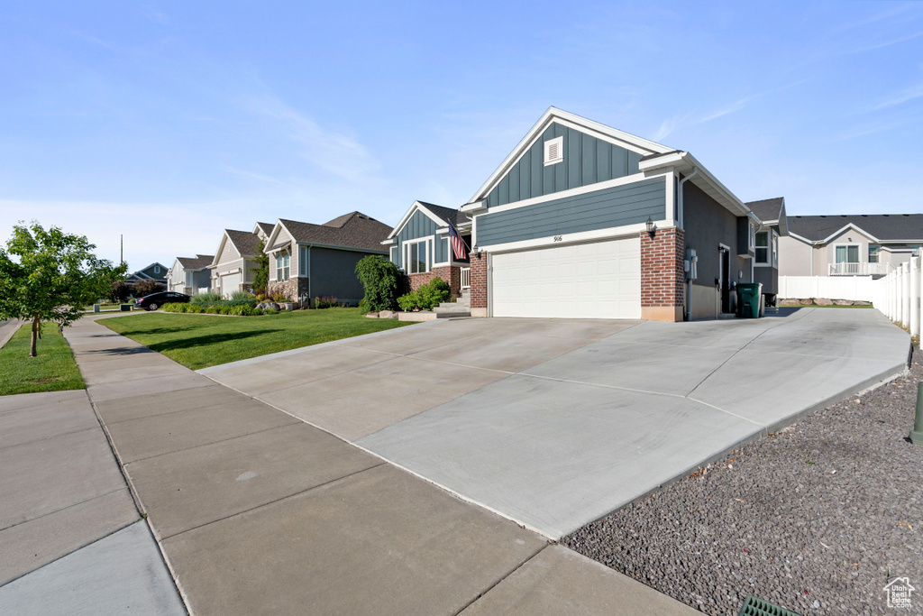 Ranch-style house featuring board and batten siding, a residential view, brick siding, and driveway