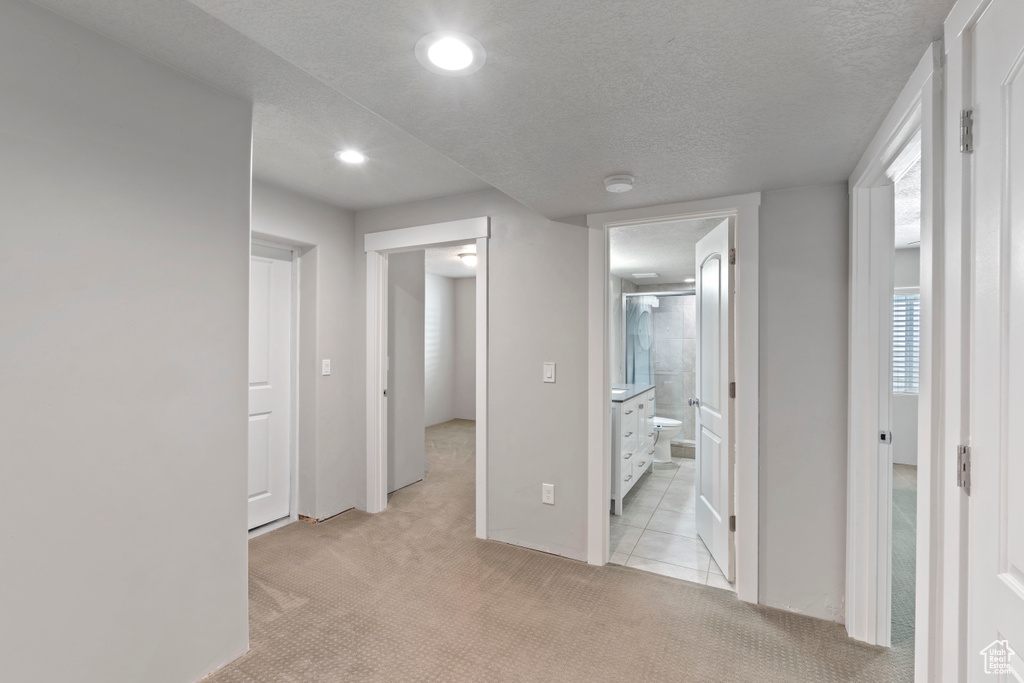 Hallway featuring light colored carpet, recessed lighting, and a textured ceiling