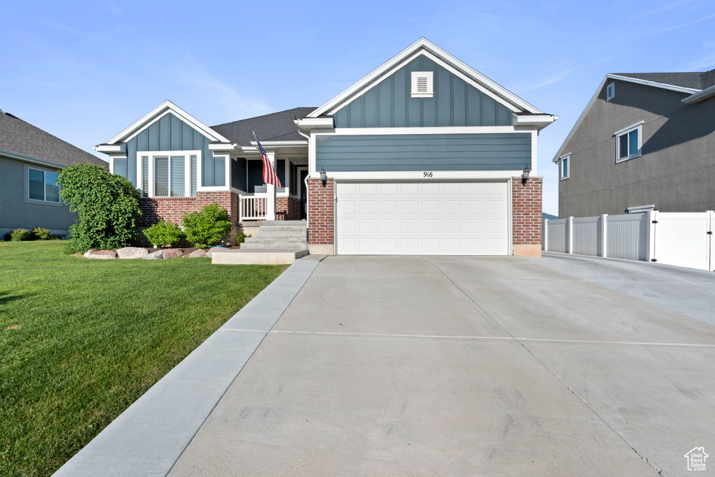 Craftsman-style home featuring board and batten siding, brick siding, driveway, and an attached garage