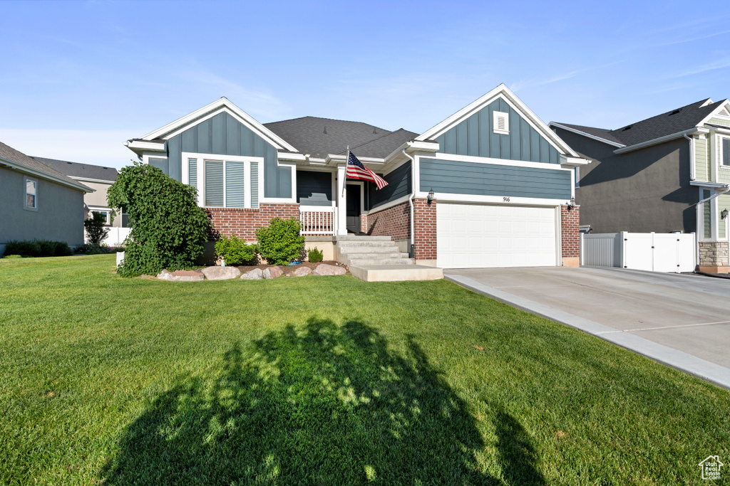 View of front of house with board and batten siding, concrete driveway, brick siding, and a gate
