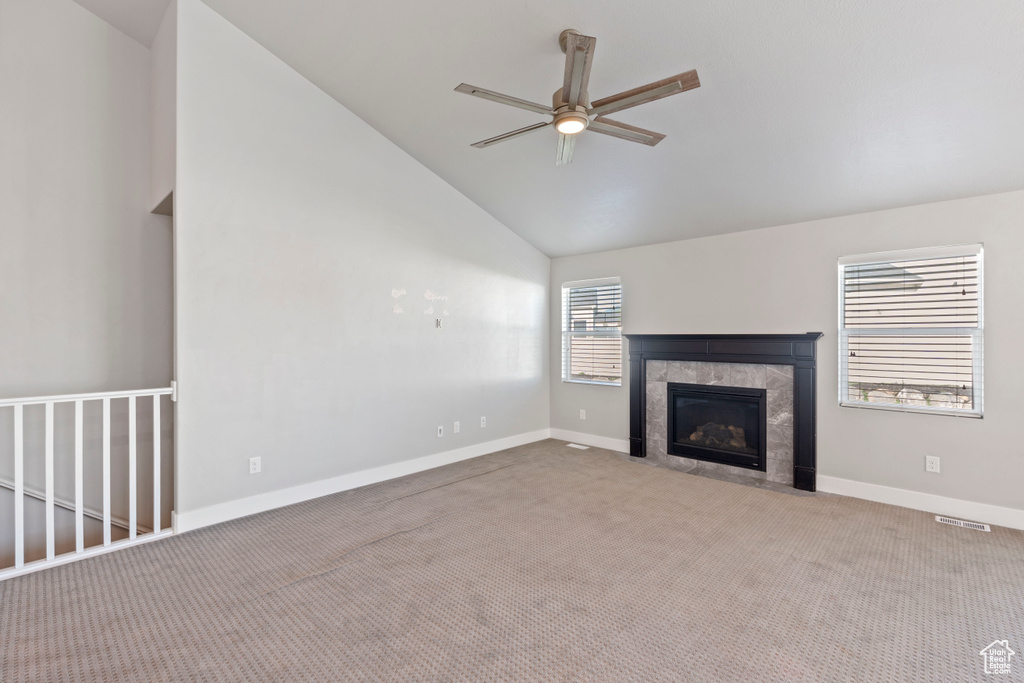 Unfurnished living room featuring a ceiling fan, carpet floors, a fireplace, and vaulted ceiling