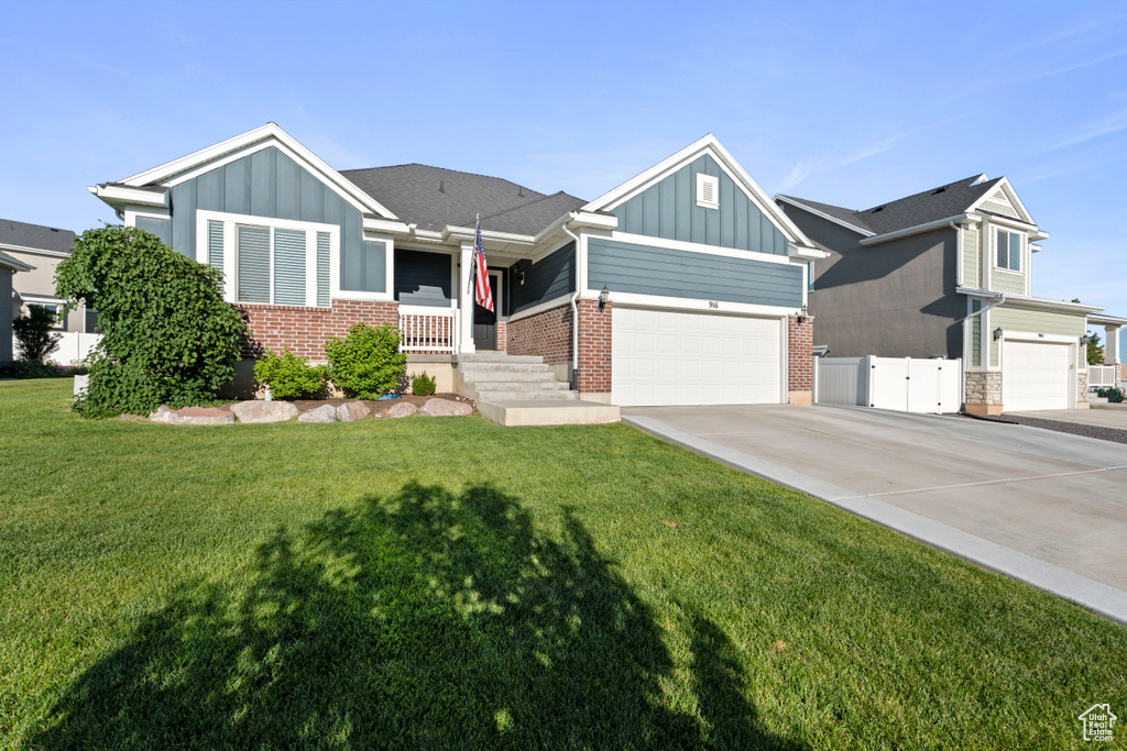 View of front of home with board and batten siding, driveway, an attached garage, and brick siding