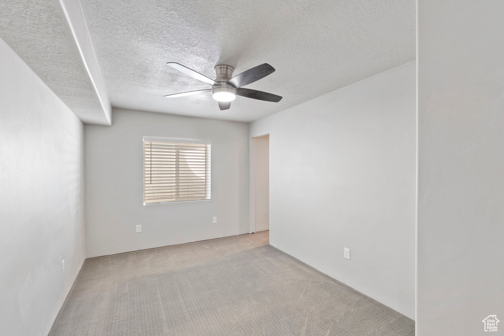 Carpeted spare room featuring a ceiling fan and a textured ceiling