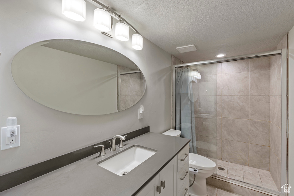 Full bath with a textured ceiling, vanity, and a stall shower