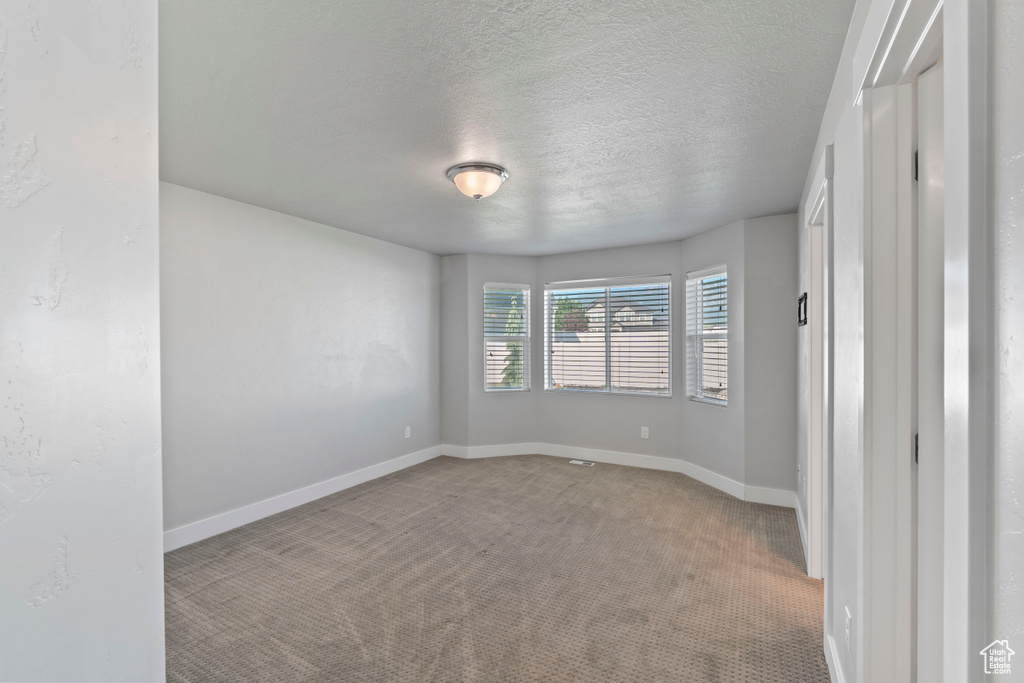 Unfurnished room featuring carpet and a textured ceiling