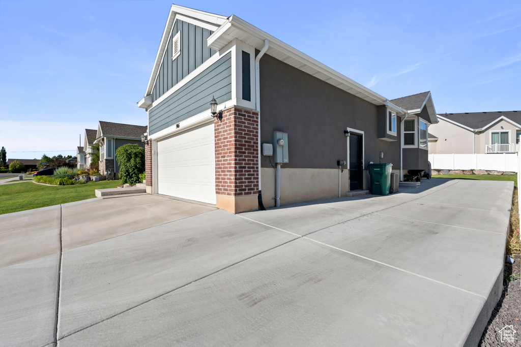 View of side of home featuring board and batten siding, driveway, a residential view, and a garage
