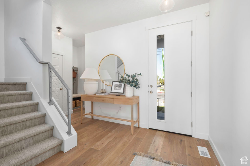 Foyer entrance with wood finished floors, plenty of natural light, and stairs