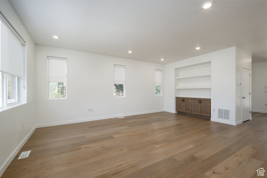 Spare room featuring built in features, light wood-style floors, and recessed lighting