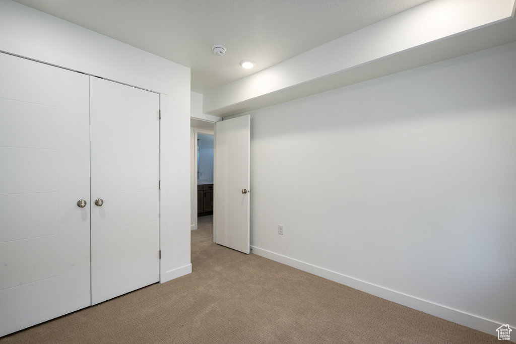 Unfurnished bedroom featuring light carpet and a closet