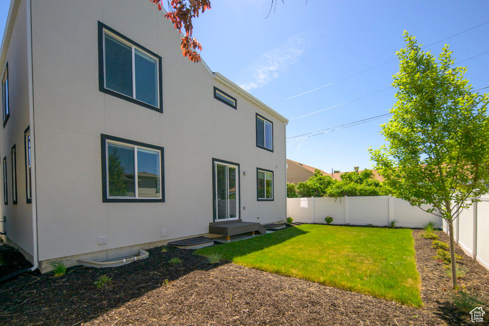 Rear view of house with a fenced backyard and stucco siding