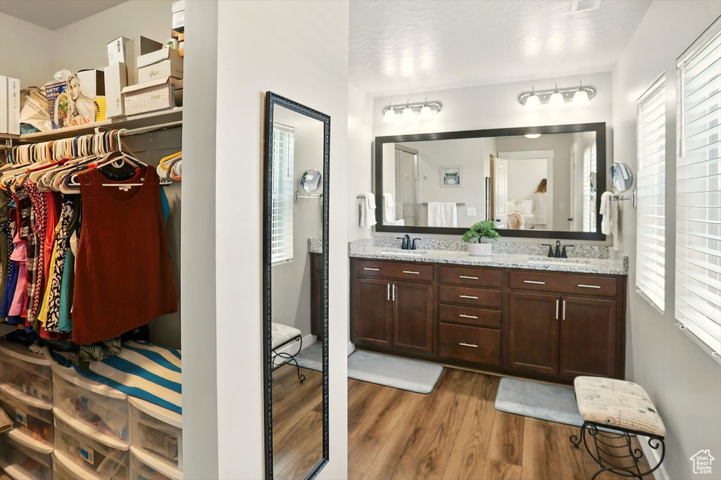 Full bathroom featuring wood finished floors, double vanity, and a walk in closet